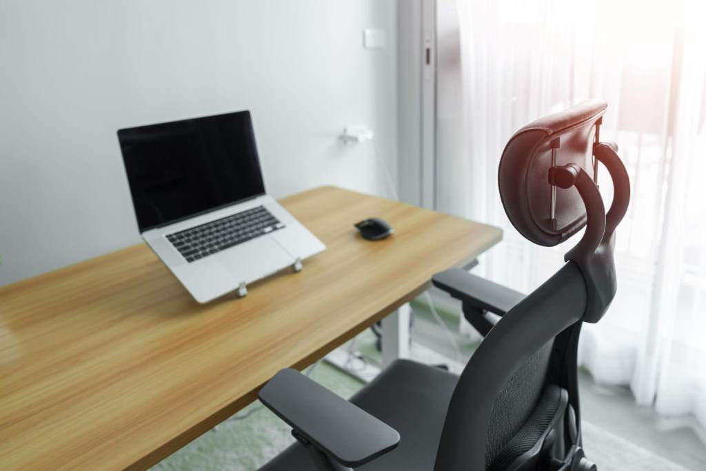 Ergonomic chair and Adjustable table with laptop computer in modern workplace