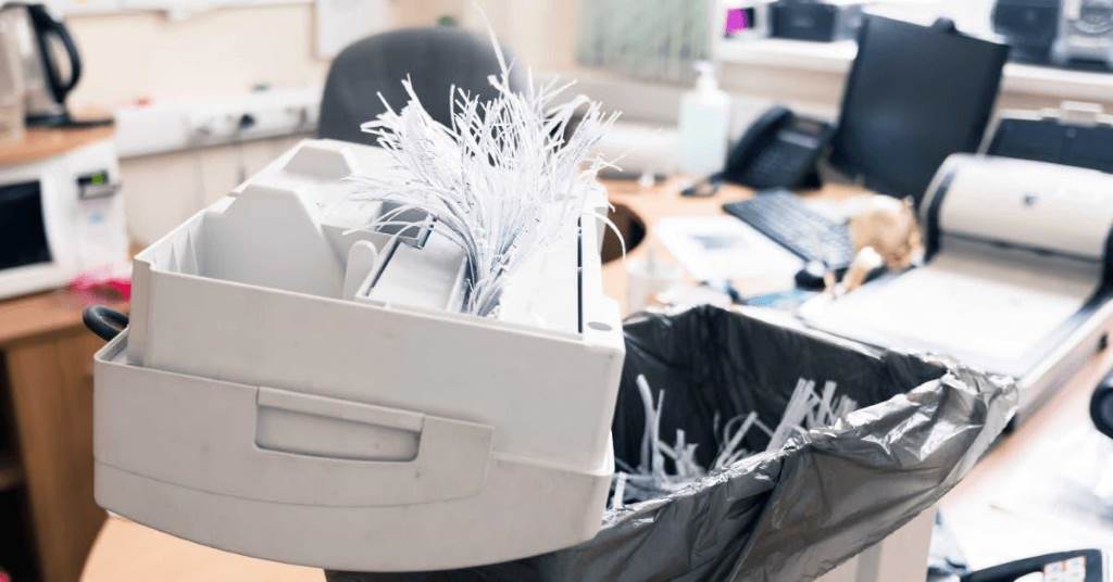 Small office shredder on desk with documents ready for secure disposal