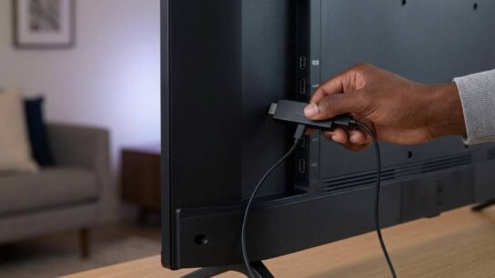 Person connecting a Fire TV Stick to a television HDMI port