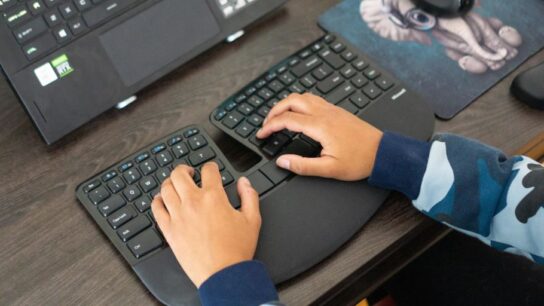 Person typing on an ergonomic keyboard designed for comfortable hand positioning and reduced strain