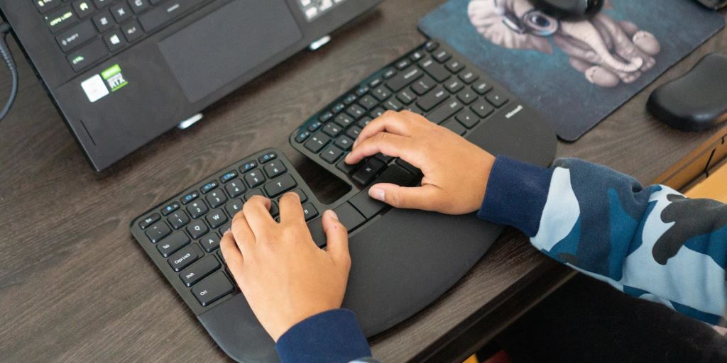 Person typing on an ergonomic keyboard designed for comfortable hand positioning and reduced strain