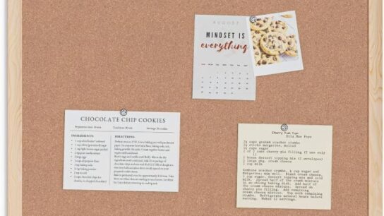U Brands cork bulletin board with light wood frame displaying notes, photos, and reminders in a New York home office