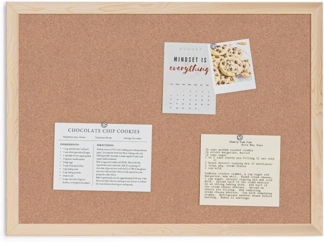 U Brands cork bulletin board with light wood frame displaying notes, photos, and reminders in a New York home office